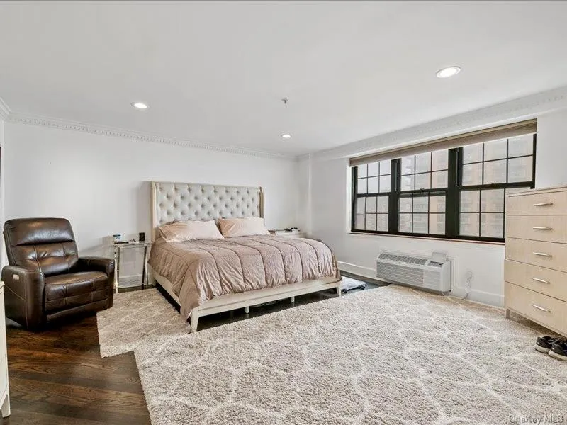 Bedroom with a wall mounted air conditioner, crown molding, baseboards, wood finished floors, and recessed lighting Bedroom with a wall mounted air conditioner, crown molding, baseboards, wood finished floors, and recessed lighting