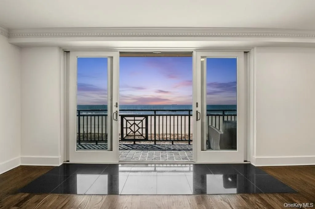 Doorway with view of water and beach and wood finished floors Doorway with view of water and beach and wood finished floors