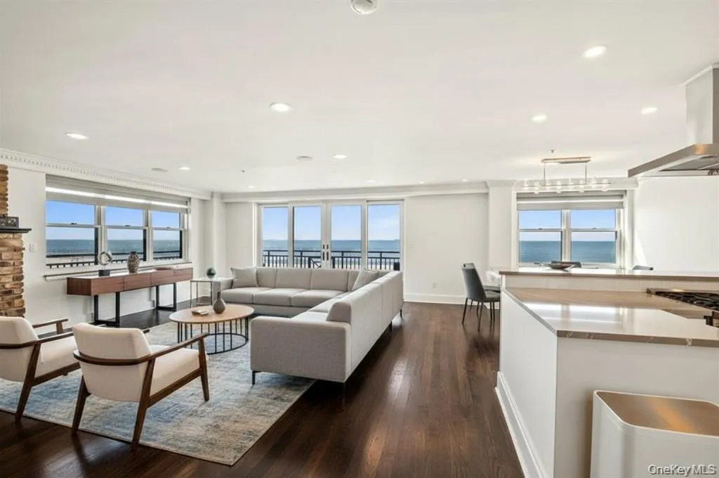 Living room featuring dark wood-style flooring, recessed lighting, and a water view Living room featuring dark wood-style flooring, recessed lighting, and a water view
