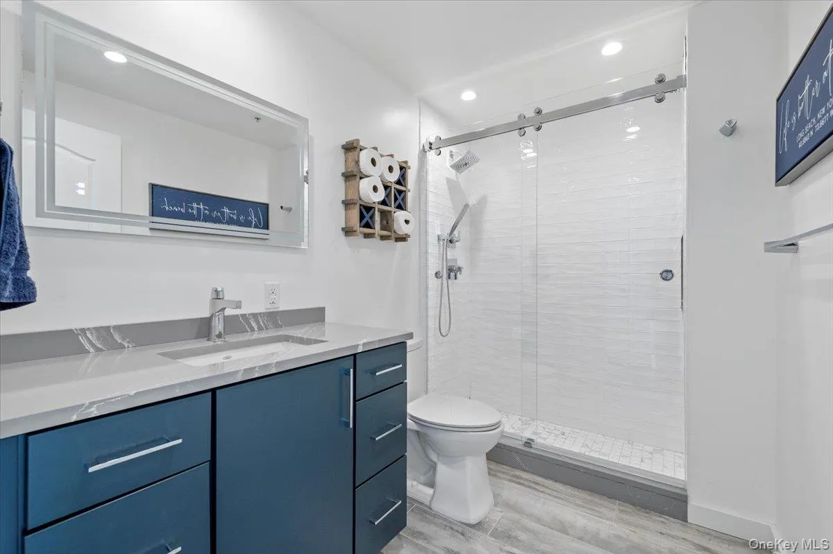 Bathroom with vanity, toilet, recessed lighting, and a shower stall Bathroom with vanity, toilet, recessed lighting, and a shower stall