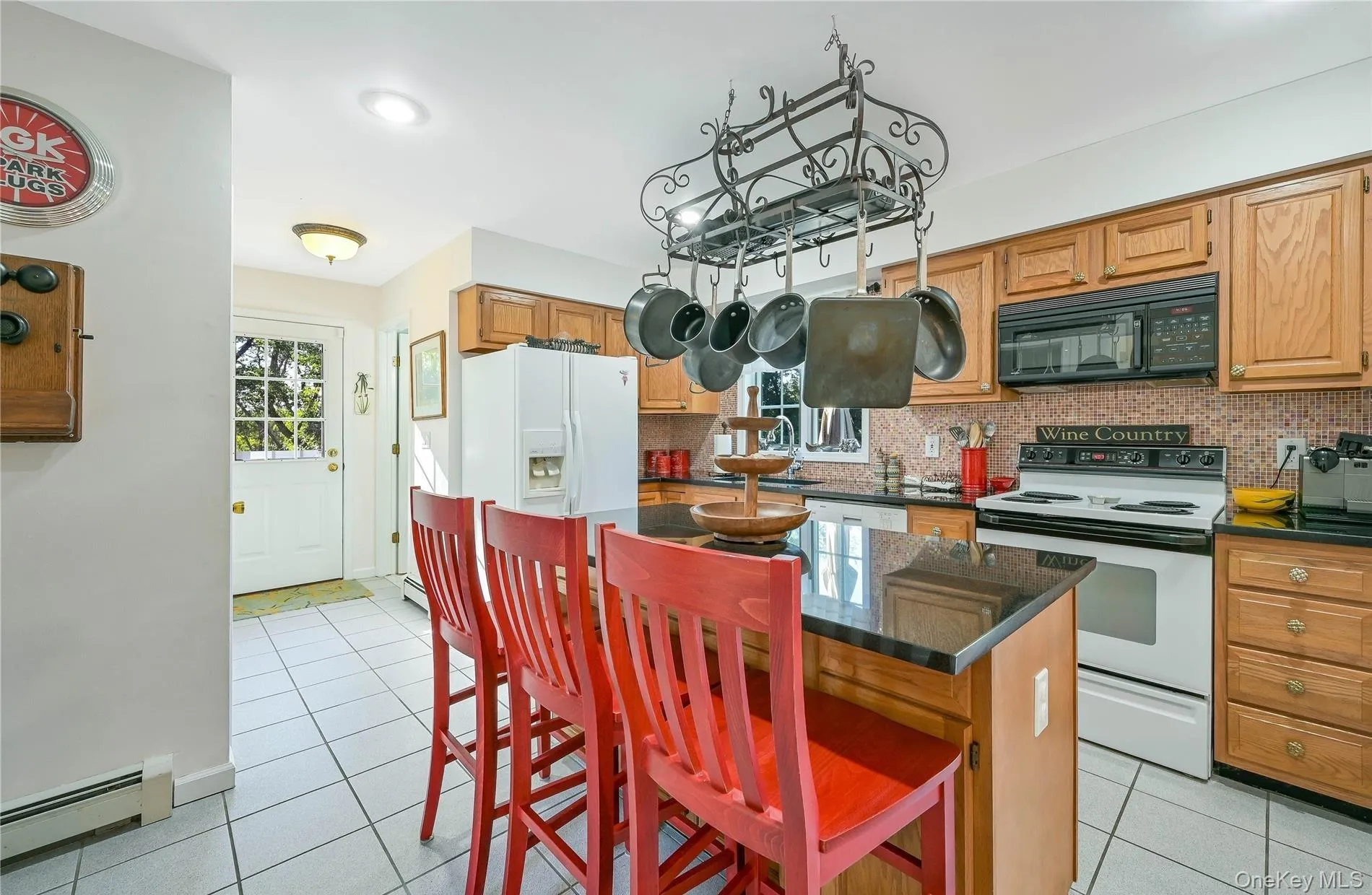 Kitchen featuring white appliances, light tile patterned floors, a center island, backsplash, and baseboard heating Kitchen featuring white appliances, light tile patterned floors, a center island, backsplash, and baseboard heating