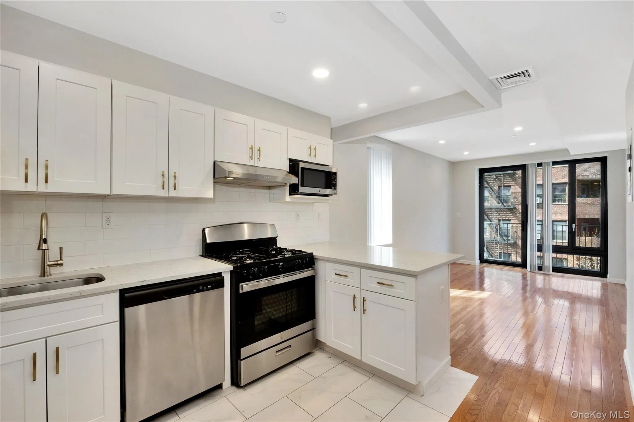Kitchen with tasteful backsplash, a peninsula, under cabinet range hood, a sink, and stainless steel appliances Kitchen with tasteful backsplash, a peninsula, under cabinet range hood, a sink, and stainless steel appliances