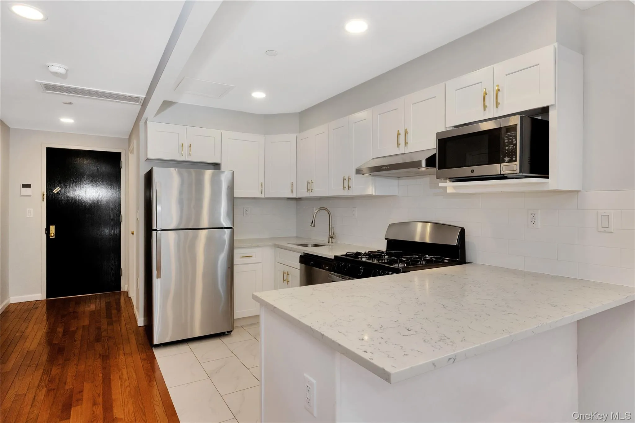 Kitchen with a peninsula, under cabinet range hood, light stone countertops, stainless steel appliances, and a sink Kitchen with a peninsula, under cabinet range hood, light stone countertops, stainless steel appliances, and a sink
