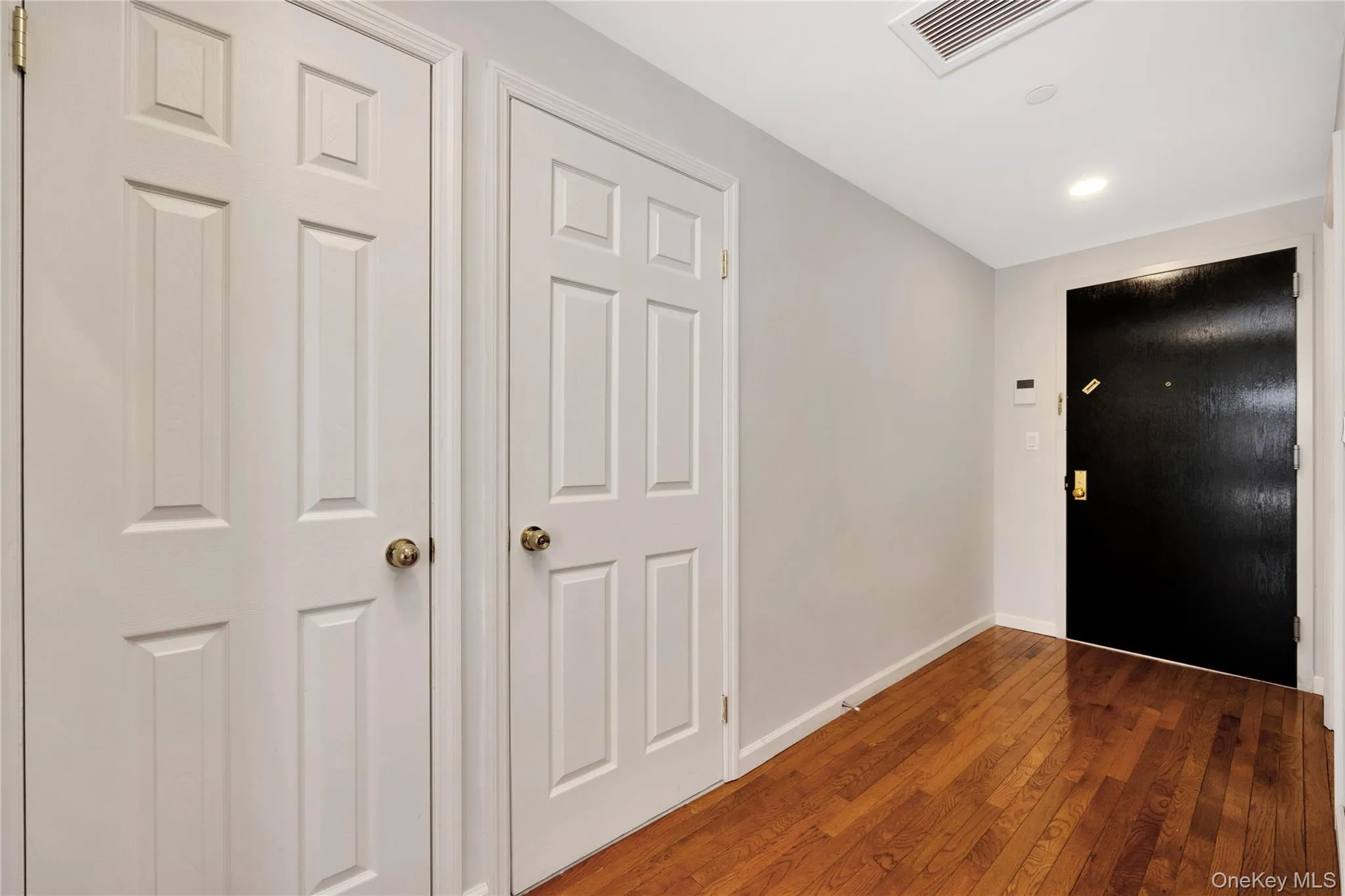 Hallway with baseboards, visible vents, and hardwood / wood-style flooring Hallway with baseboards, visible vents, and hardwood / wood-style flooring