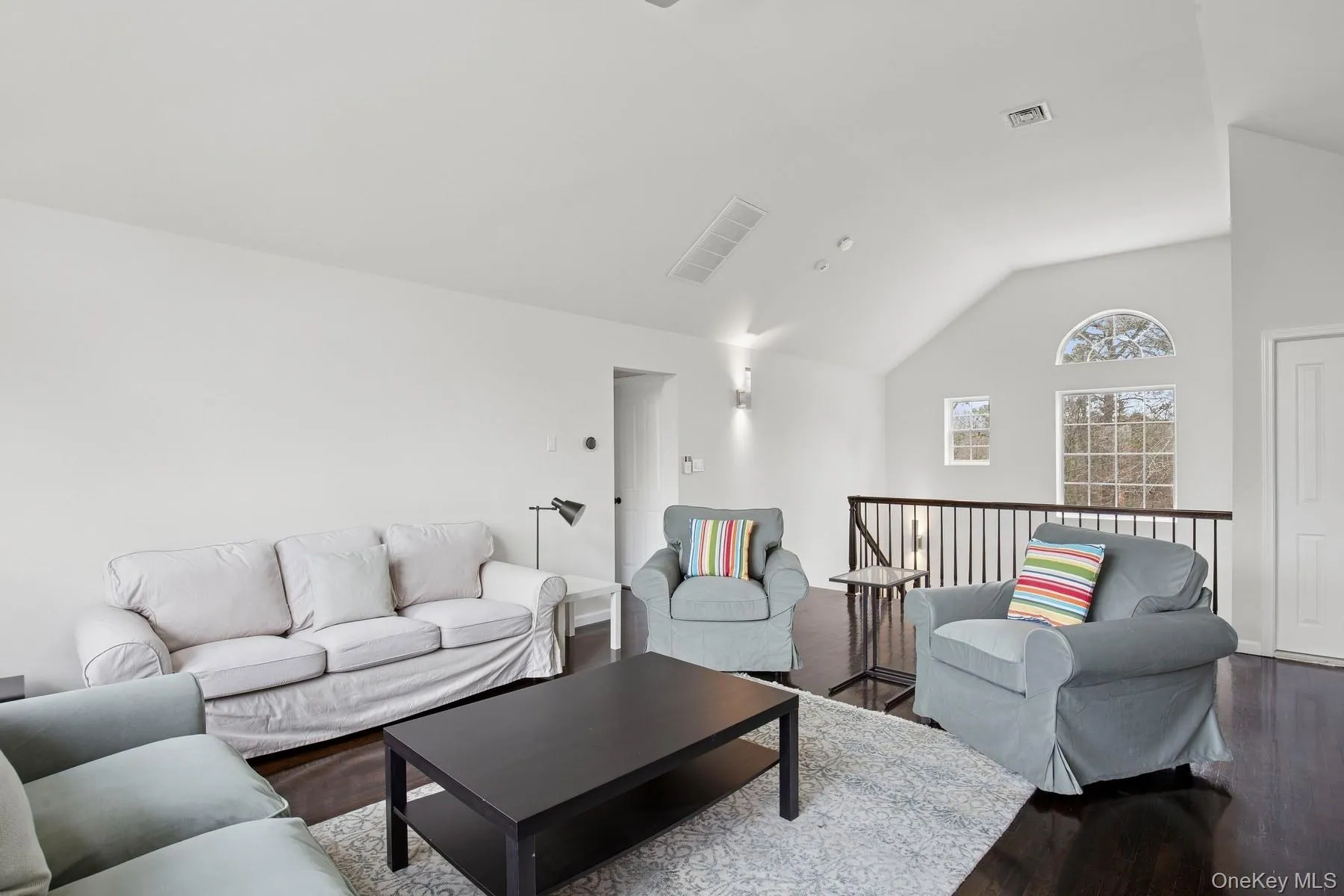 Living room featuring dark wood-type flooring, visible vents, and vaulted ceiling Living room featuring dark wood-type flooring, visible vents, and vaulted ceiling
