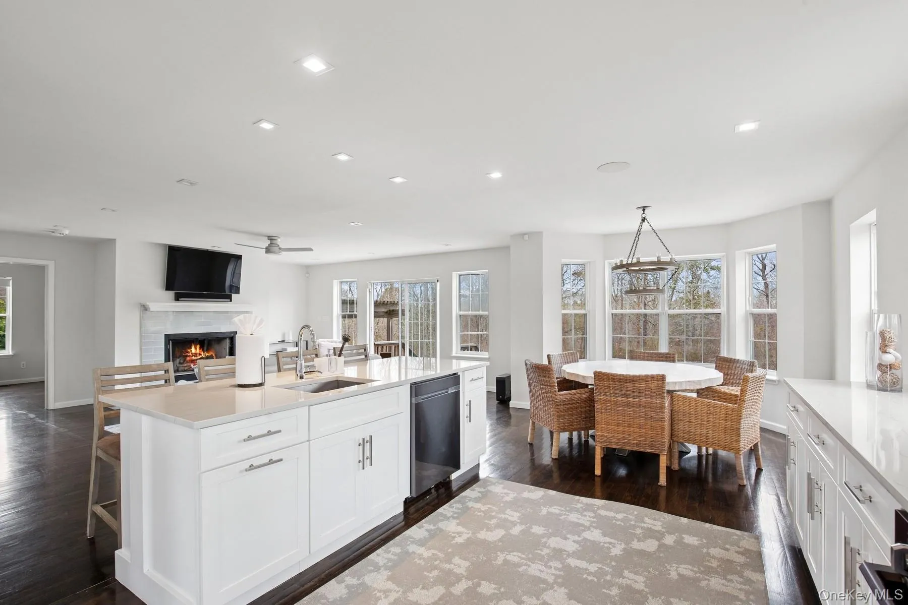 Kitchen with dark wood-style flooring, a lit fireplace, a ceiling fan, dishwasher, and a sink Kitchen with dark wood-style flooring, a lit fireplace, a ceiling fan, dishwasher, and a sink