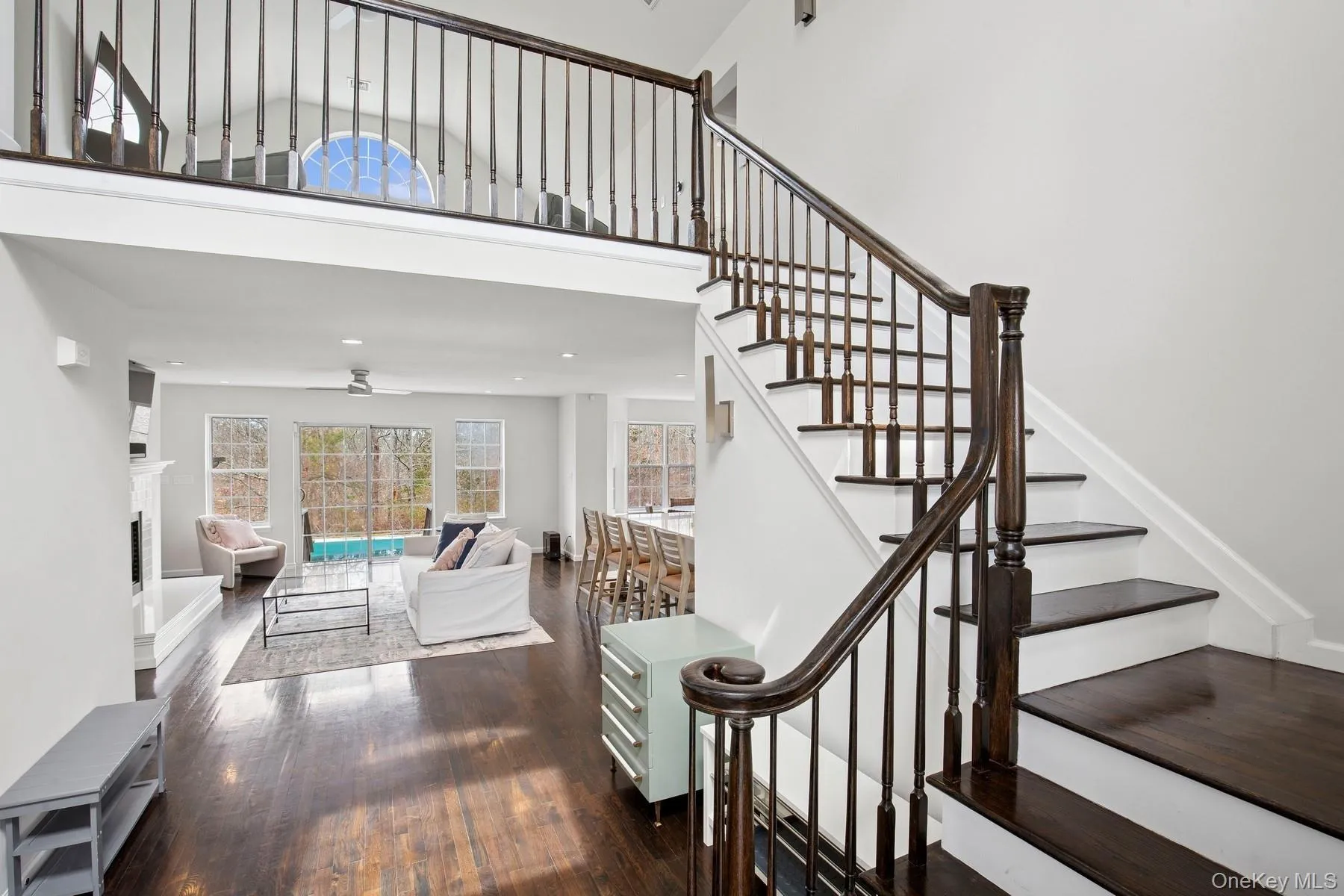 Stairs with a fireplace, a ceiling fan, recessed lighting, a high ceiling, and wood-type flooring Stairs with a fireplace, a ceiling fan, recessed lighting, a high ceiling, and wood-type flooring