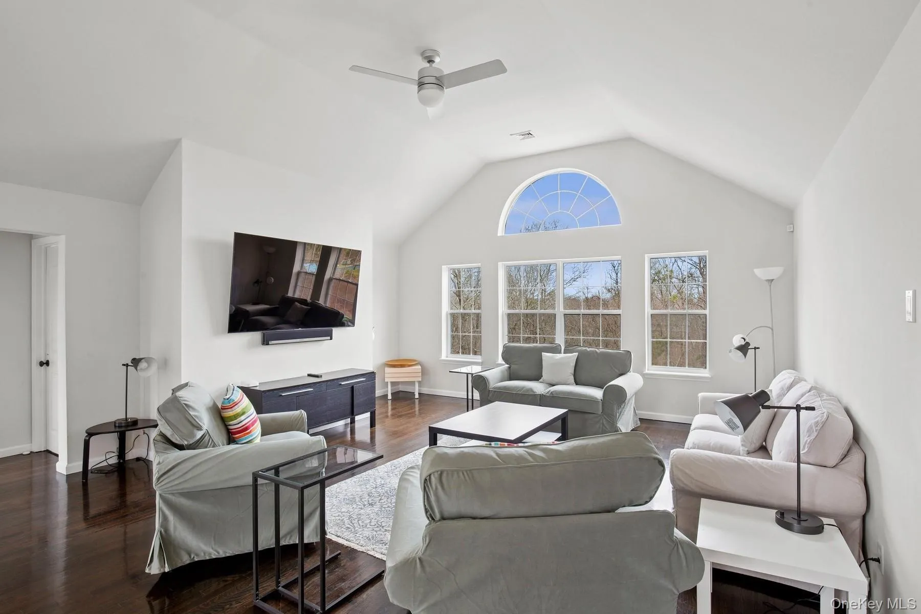 Living area featuring visible vents, baseboards, a ceiling fan, dark wood finished floors, and vaulted ceiling Living area featuring visible vents, baseboards, a ceiling fan, dark wood finished floors, and vaulted ceiling