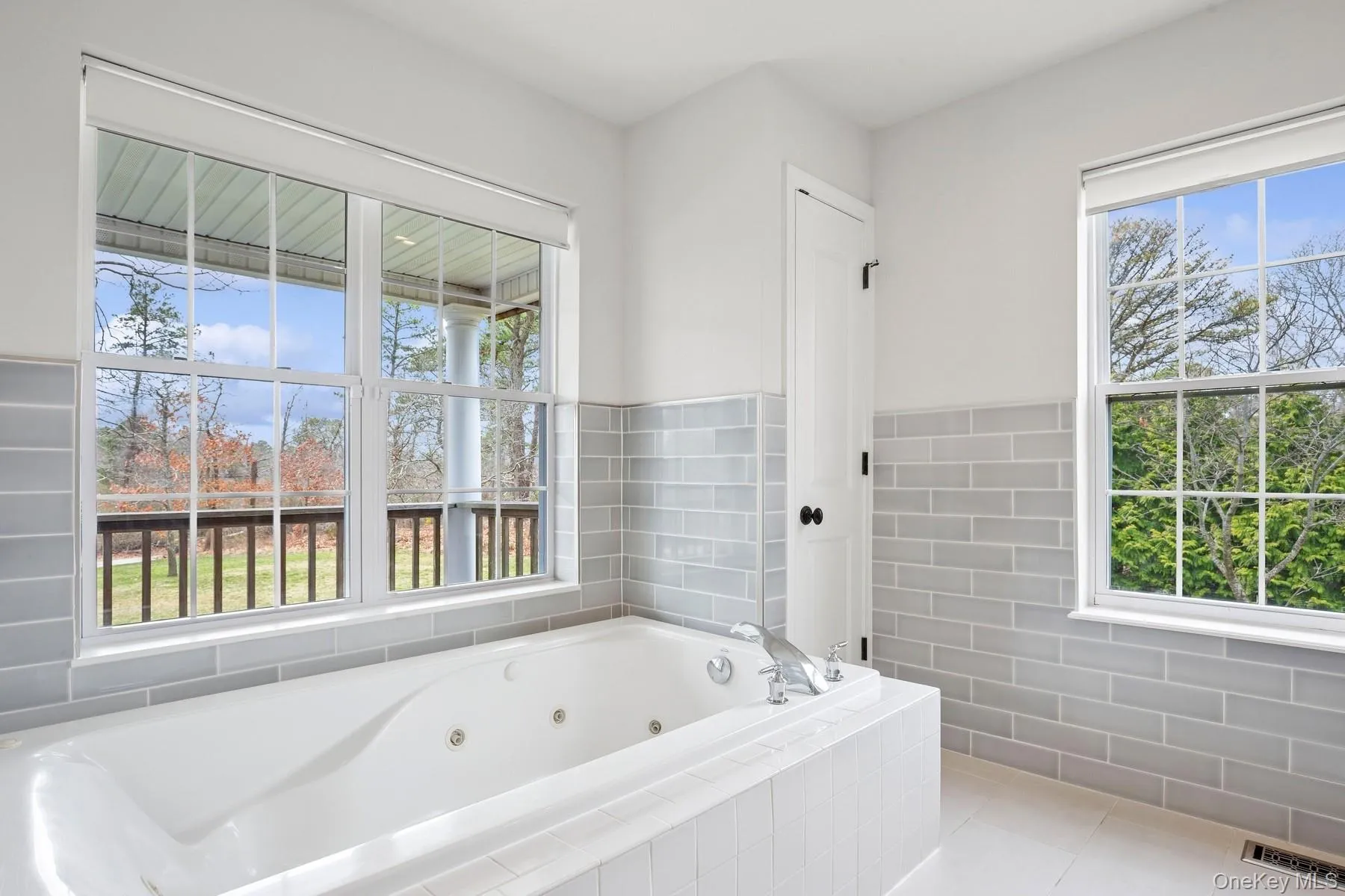 Bathroom with visible vents, tile walls, a whirlpool tub, and tile patterned flooring Bathroom with visible vents, tile walls, a whirlpool tub, and tile patterned flooring