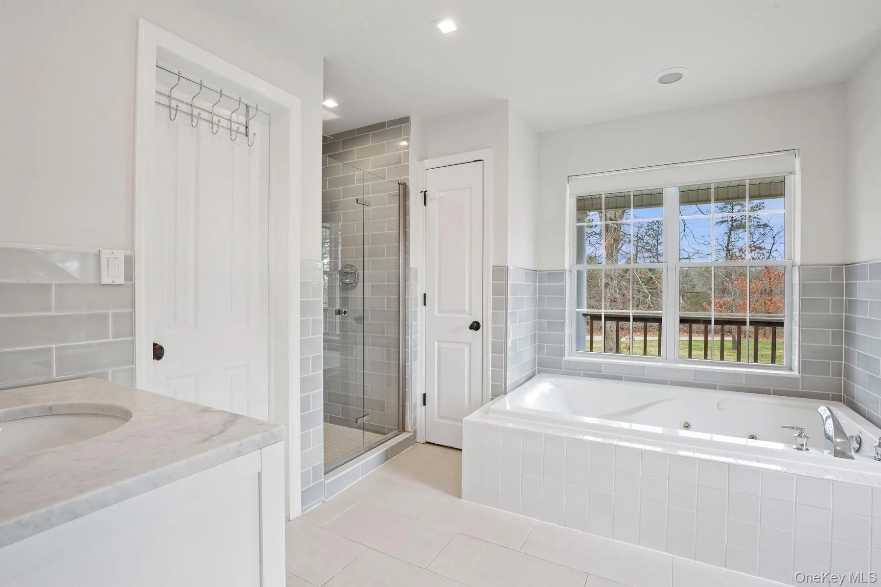 Bathroom with a stall shower, vanity, a tub with jets, and tile patterned floors Bathroom with a stall shower, vanity, a tub with jets, and tile patterned floors