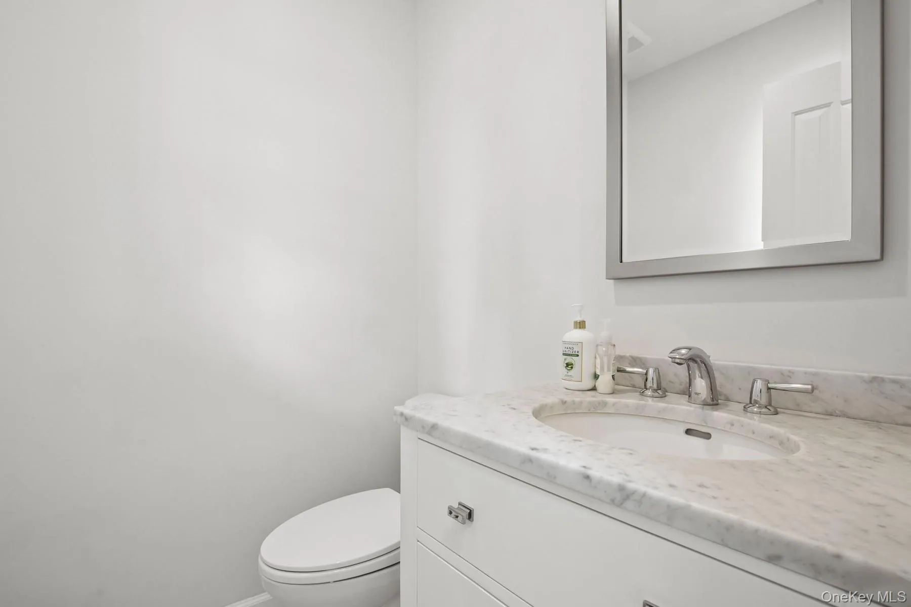 Bathroom featuring toilet, vanity, and baseboards Bathroom featuring toilet, vanity, and baseboards