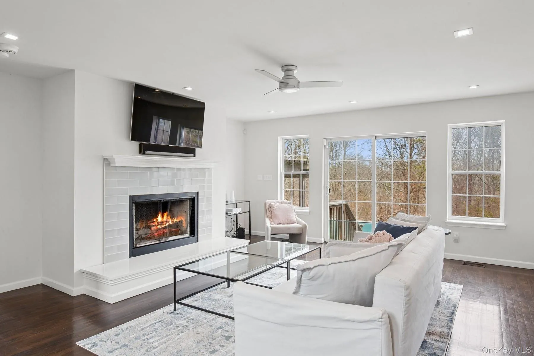 Living room with ceiling fan, baseboards, wood finished floors, and a warm lit fireplace Living room with ceiling fan, baseboards, wood finished floors, and a warm lit fireplace