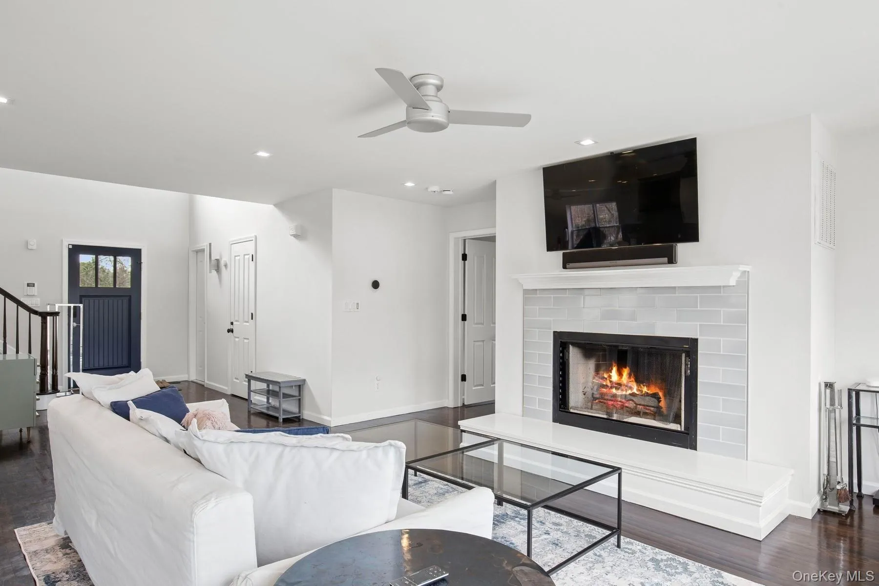 Living area featuring recessed lighting, stairway, a brick fireplace, ceiling fan, and wood finished floors Living area featuring recessed lighting, stairway, a brick fireplace, ceiling fan, and wood finished floors