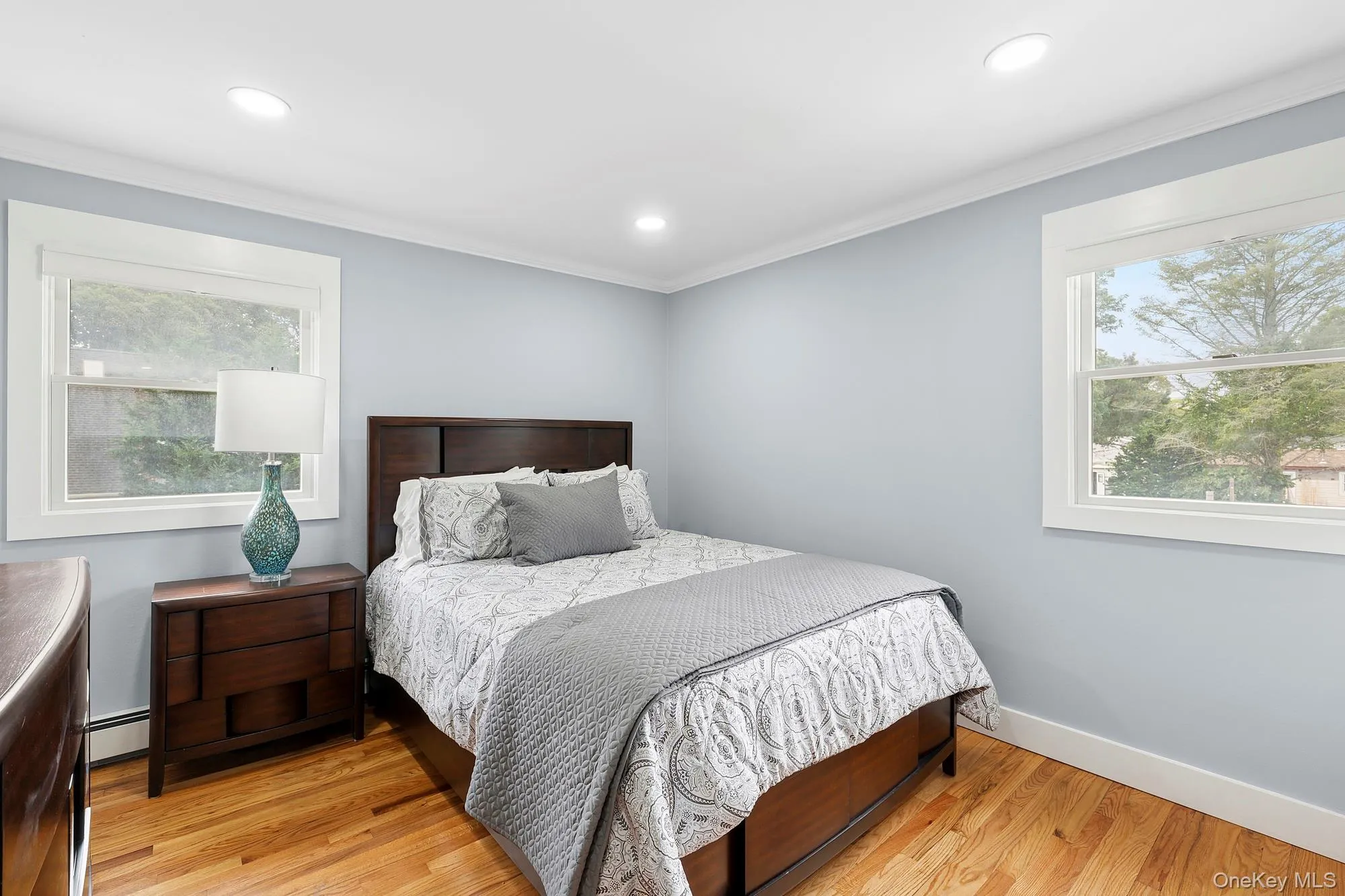 Bedroom featuring light wood-style floors, crown molding, recessed lighting, and a baseboard heating unit Bedroom featuring light wood-style floors, crown molding, recessed lighting, and a baseboard heating unit