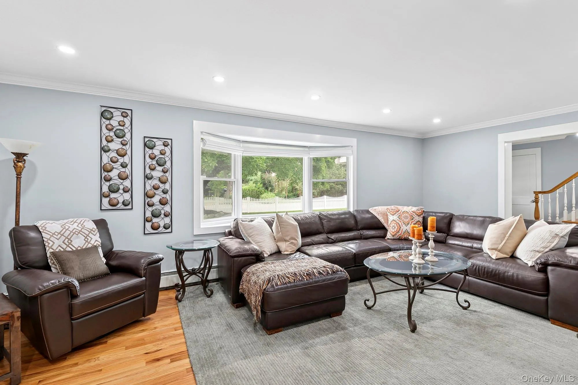 Living room with ornamental molding, light wood-type flooring, recessed lighting, stairway, and a baseboard heating unit Living room with ornamental molding, light wood-type flooring, recessed lighting, stairway, and a baseboard heating unit