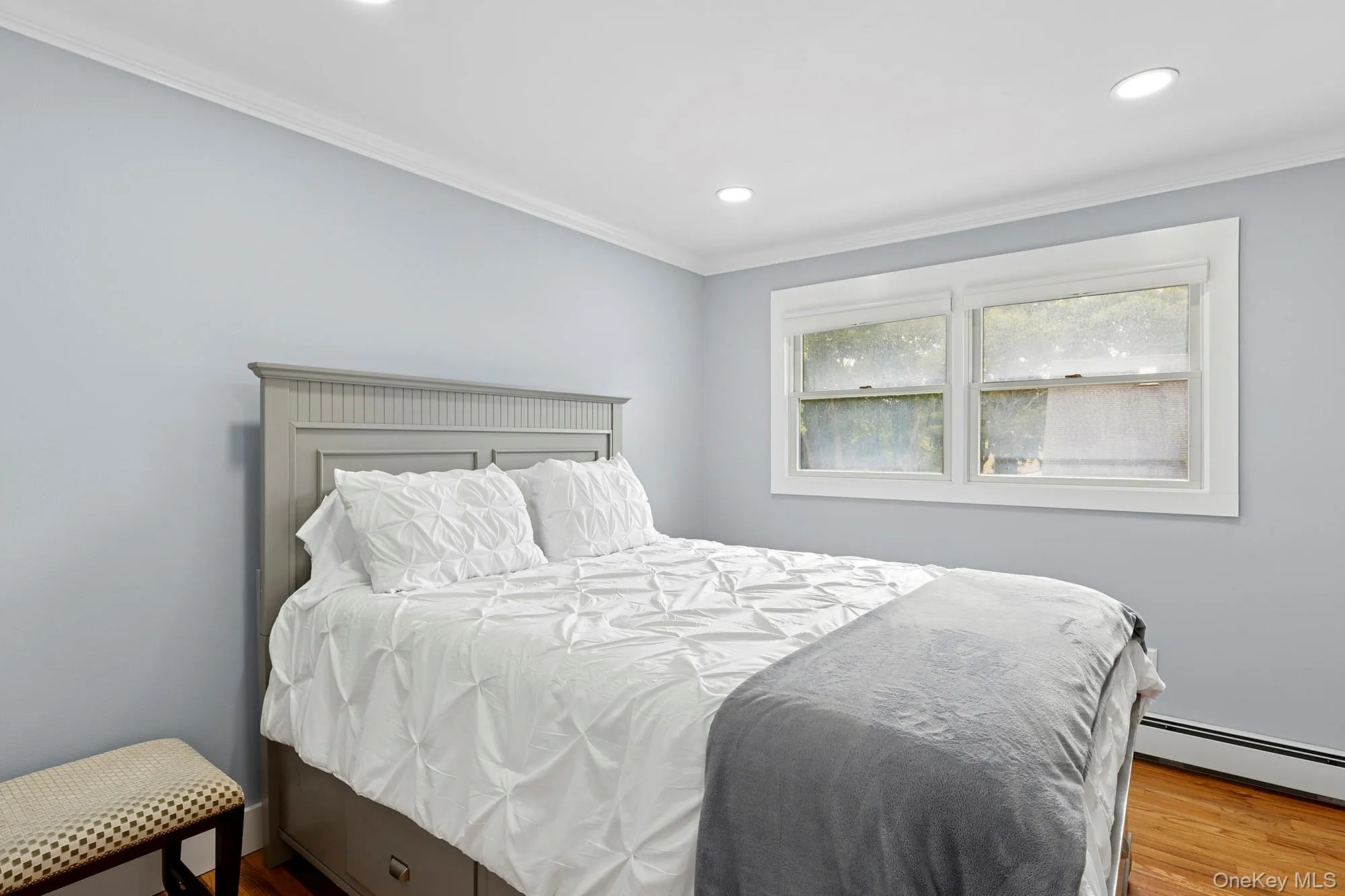 Bedroom with ornamental molding, wood finished floors, baseboard heating, and recessed lighting Bedroom with ornamental molding, wood finished floors, baseboard heating, and recessed lighting