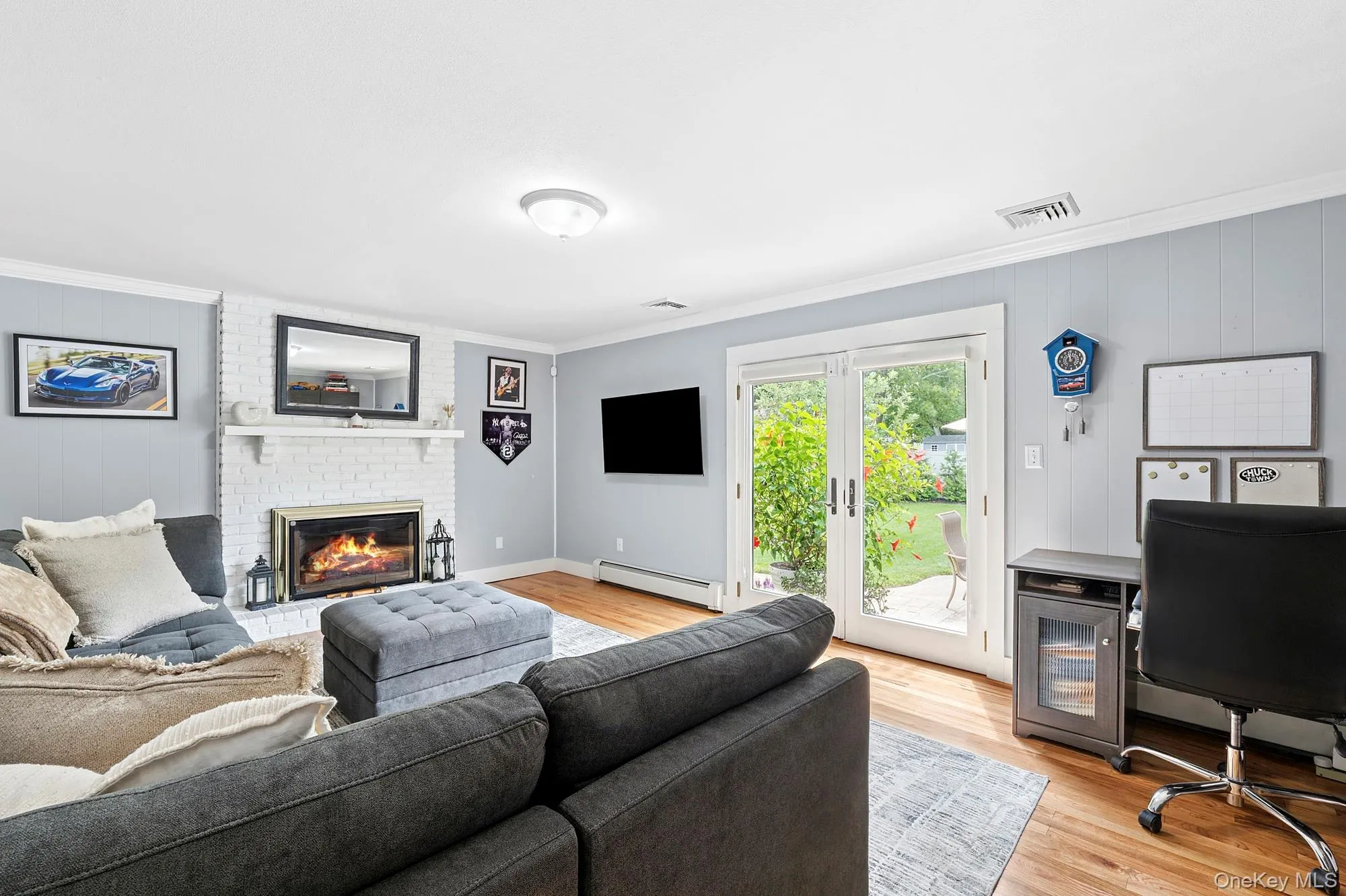 Living area with light wood-style flooring, crown molding, access to the backyard, and a gas fireplace Living area with light wood-style flooring, crown molding, access to the backyard, and a gas fireplace