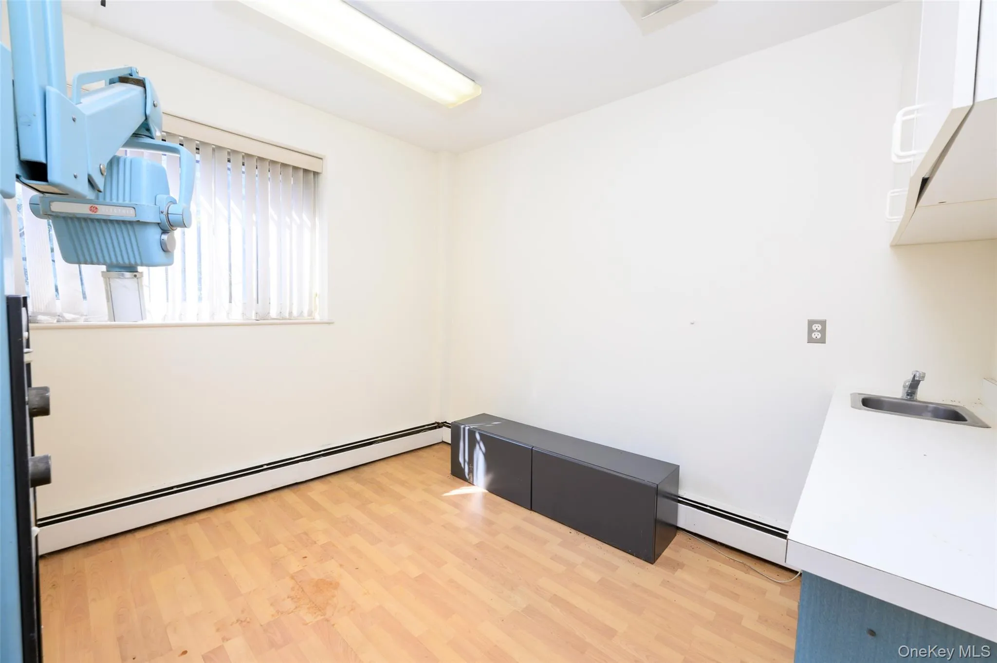 Empty room with a baseboard heating unit, a sink, and light wood-style floors Empty room with a baseboard heating unit, a sink, and light wood-style floors