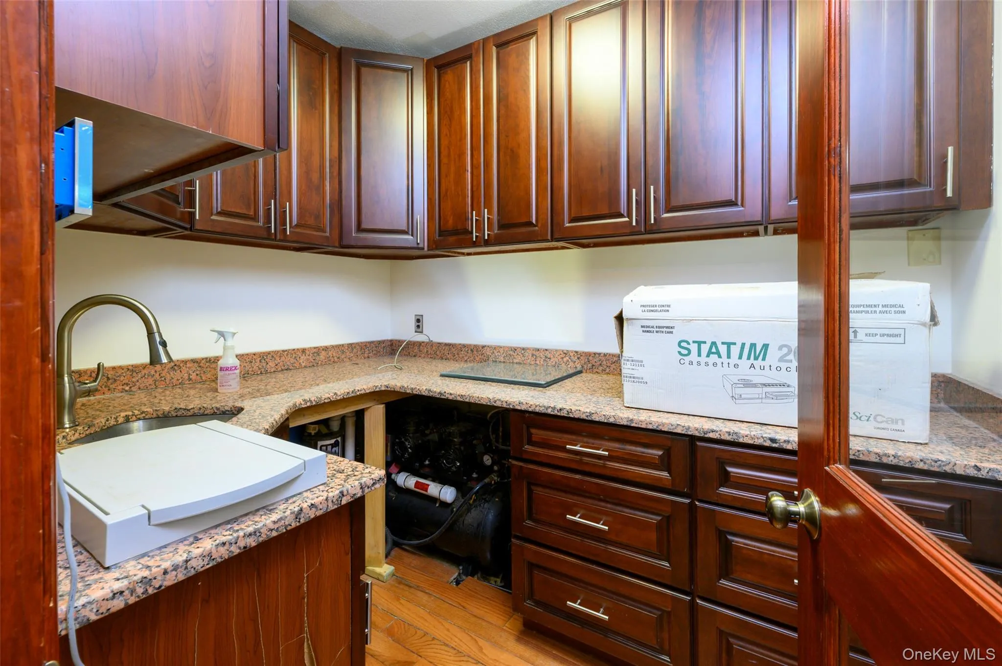 Kitchen with light stone countertops, light wood finished floors, a sink, and built in study area Kitchen with light stone countertops, light wood finished floors, a sink, and built in study area