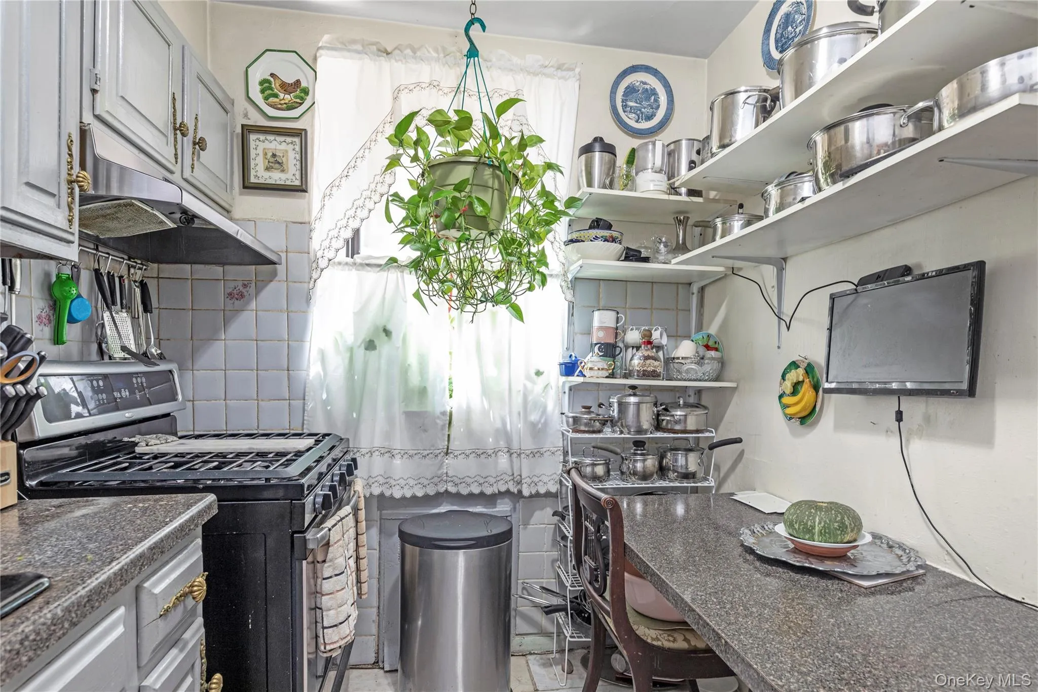 Kitchen featuring black gas range oven, under cabinet range hood, tile walls, backsplash, and open shelves Kitchen featuring black gas range oven, under cabinet range hood, tile walls, backsplash, and open shelves