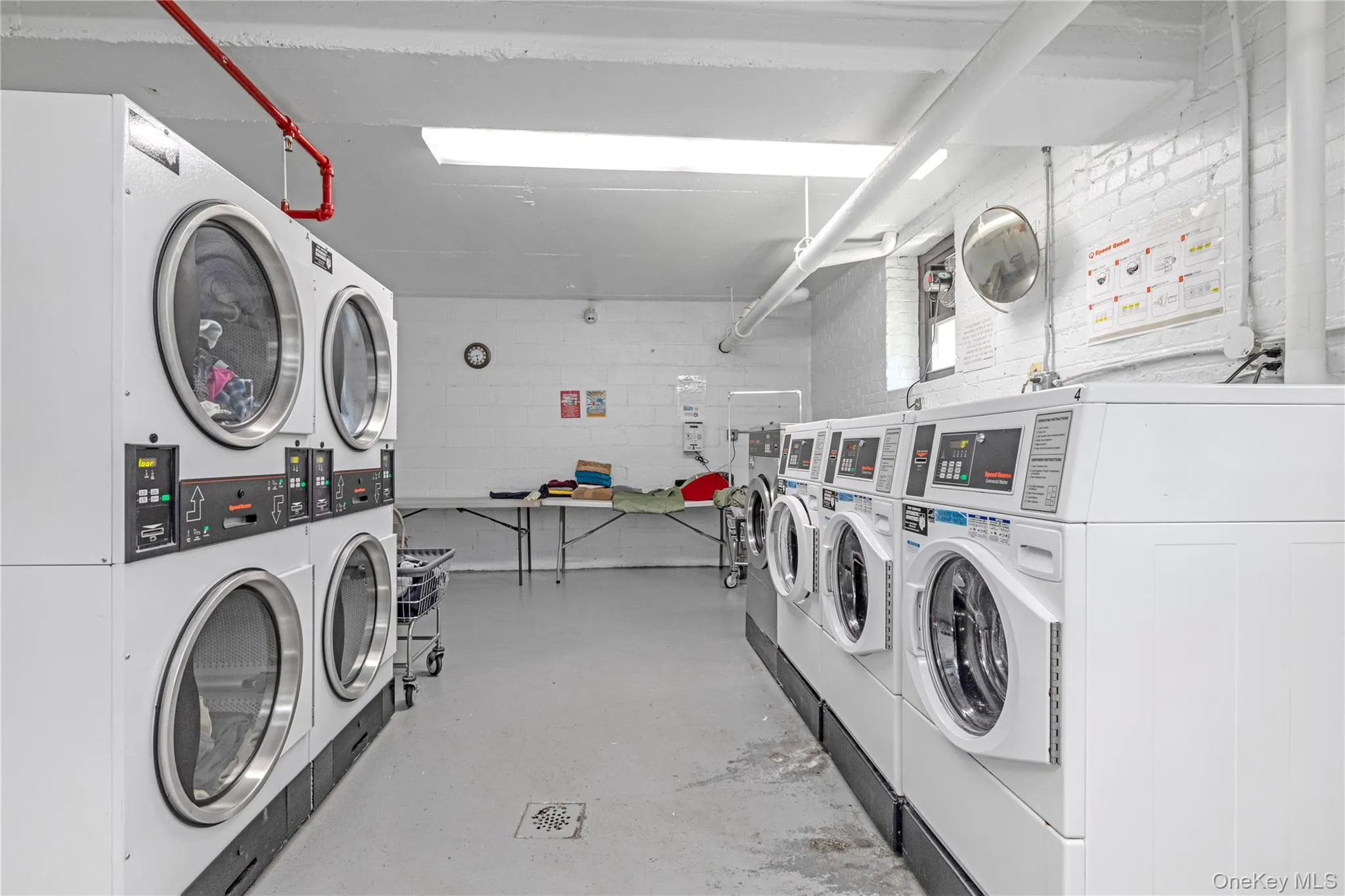 Community laundry room with stacked washer / drying machine, separate washer and dryer, and concrete block wall Community laundry room with stacked washer / drying machine, separate washer and dryer, and concrete block wall