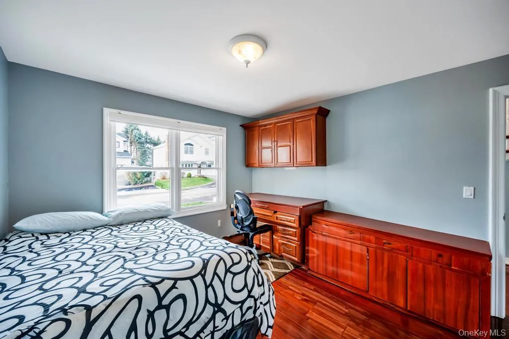 Bedroom with dark wood-type flooring and built in study area Bedroom with dark wood-type flooring and built in study area
