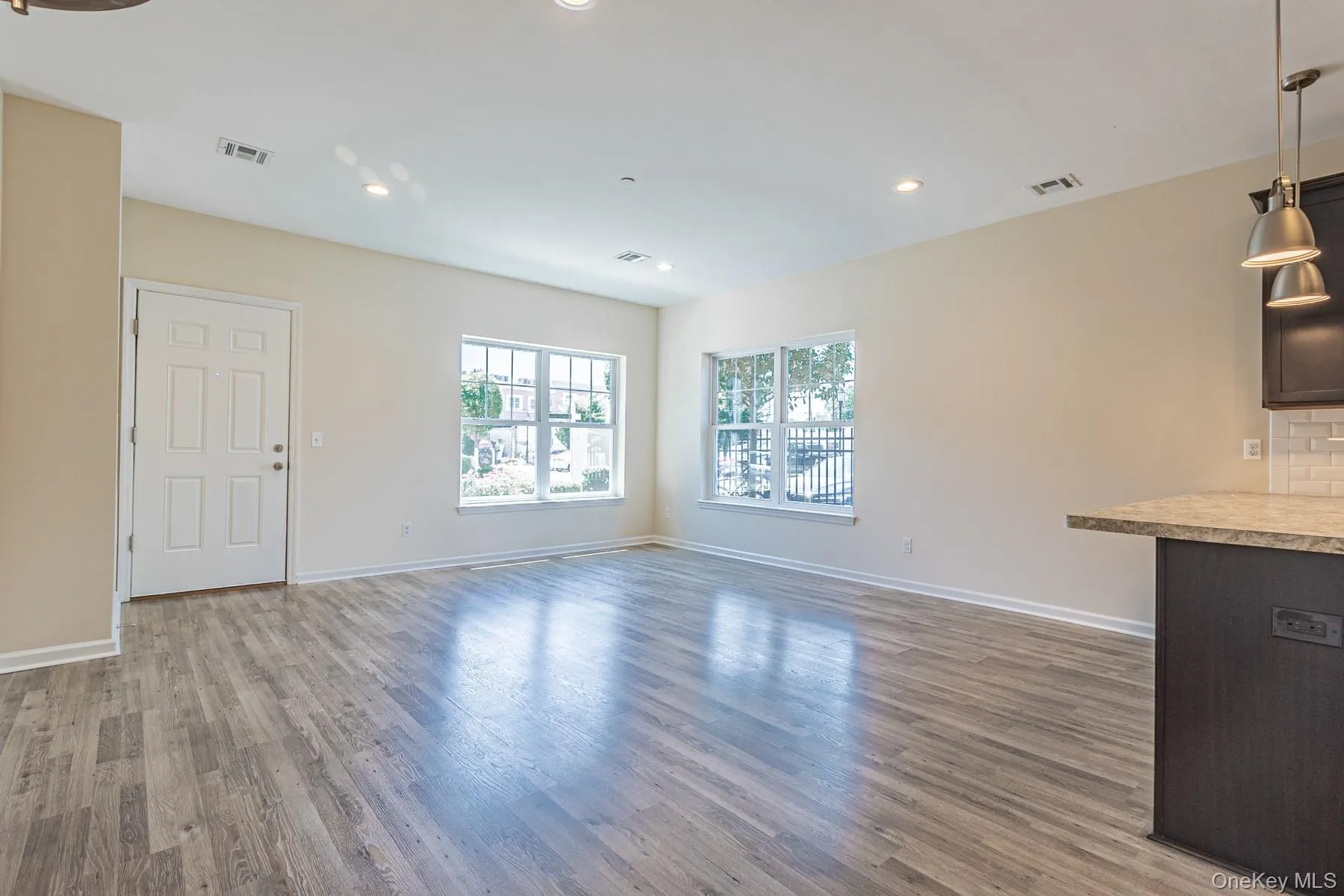 Unfurnished living room with recessed lighting, visible vents, baseboards, and wood finished floors Unfurnished living room with recessed lighting, visible vents, baseboards, and wood finished floors