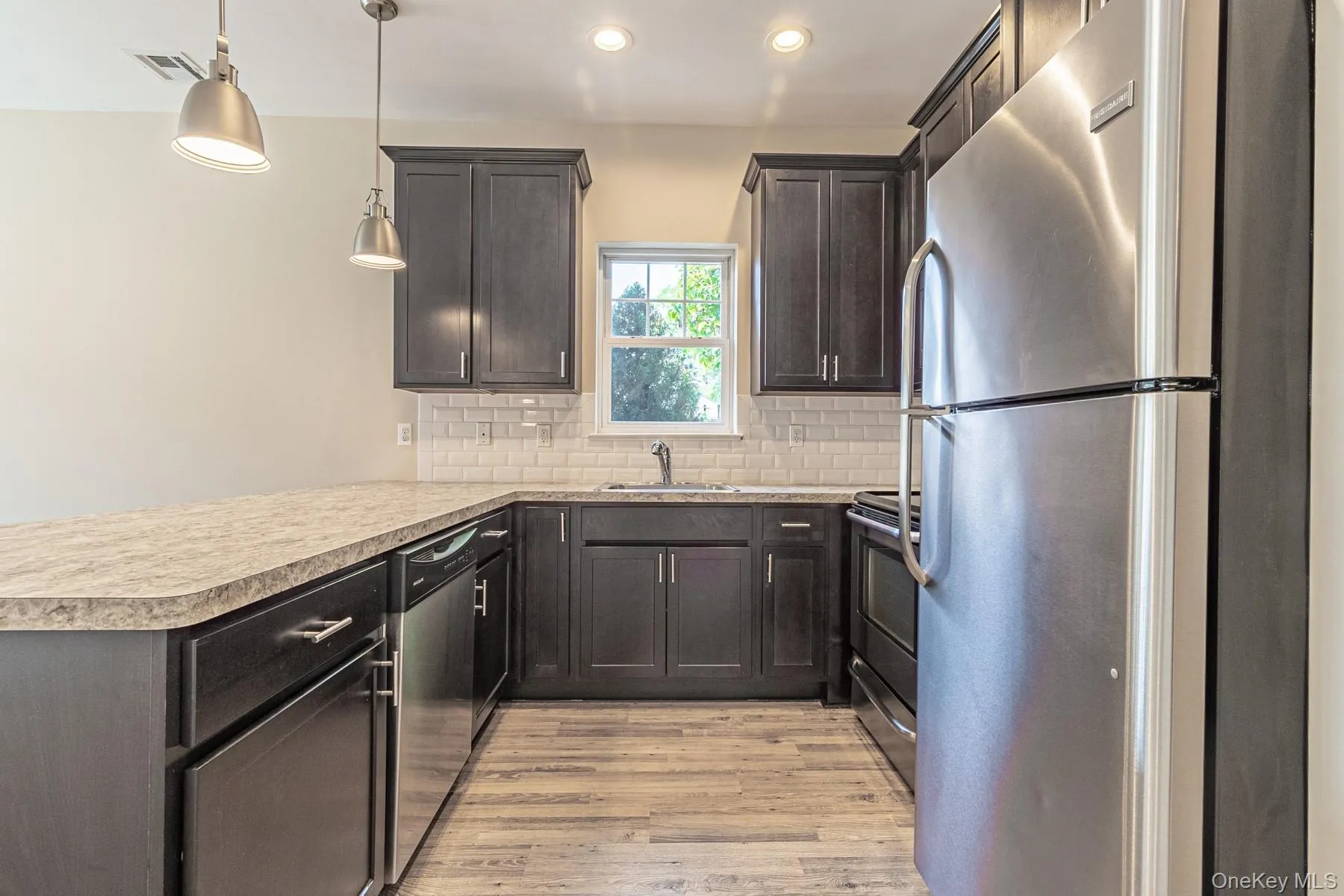 Kitchen with a sink, light wood-type flooring, a peninsula, stainless steel appliances, and decorative backsplash Kitchen with a sink, light wood-type flooring, a peninsula, stainless steel appliances, and decorative backsplash