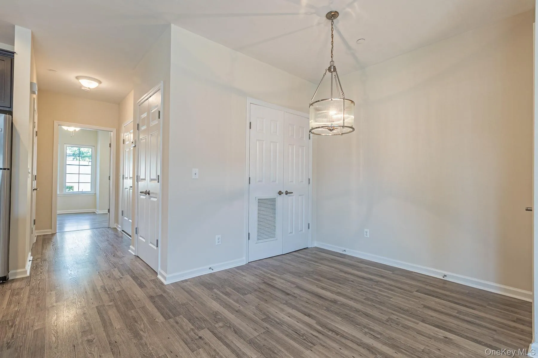 Unfurnished dining area featuring dark wood-style flooring, visible vents, and baseboards Unfurnished dining area featuring dark wood-style flooring, visible vents, and baseboards