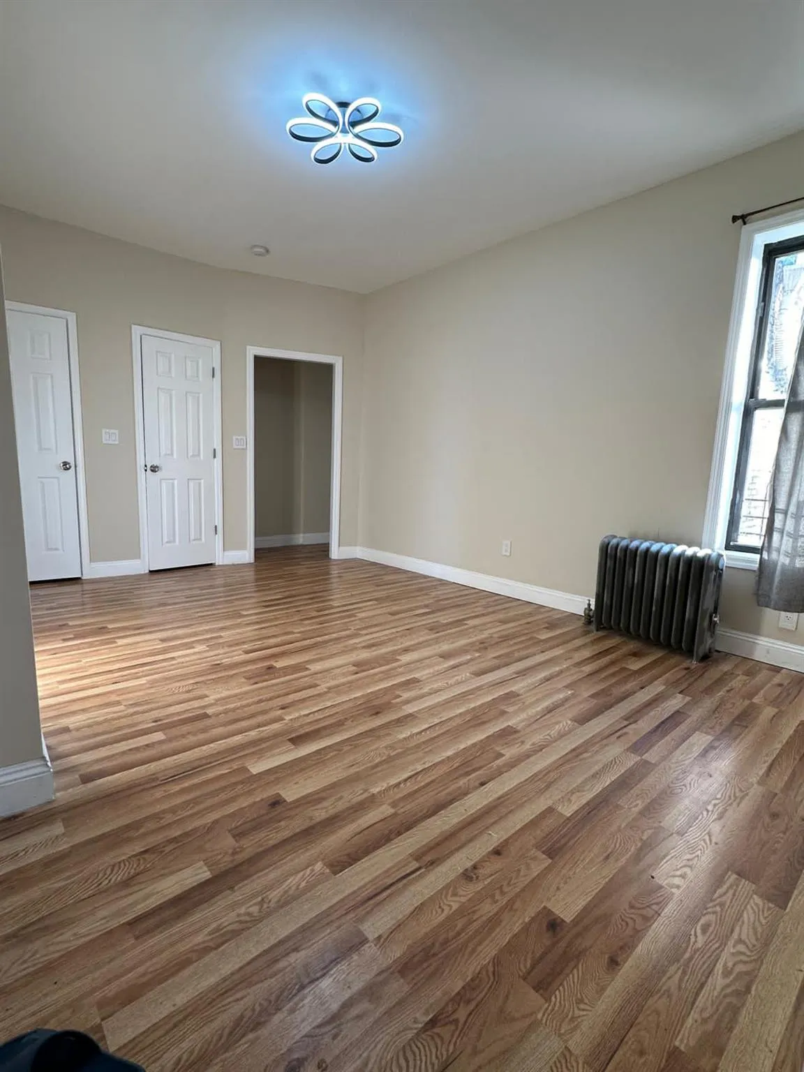 Spare room with baseboards, radiator, and wood finished floors Spare room with baseboards, radiator, and wood finished floors