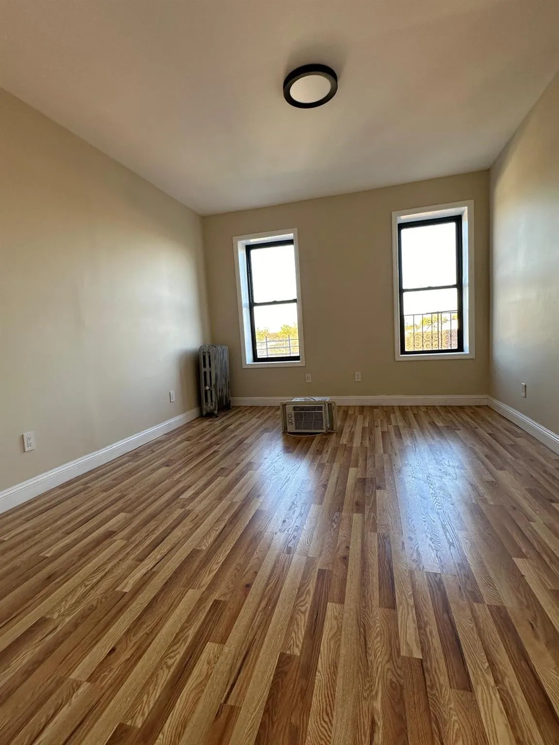 Spare room with wood finished floors, a wall unit AC, and baseboards Spare room with wood finished floors, a wall unit AC, and baseboards