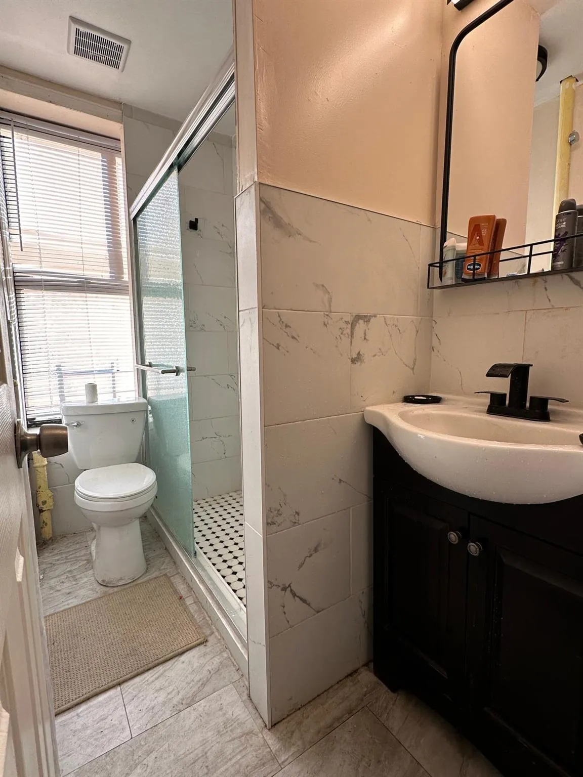 Bathroom featuring vanity, toilet, a shower stall, visible vents, and tile walls Bathroom featuring vanity, toilet, a shower stall, visible vents, and tile walls