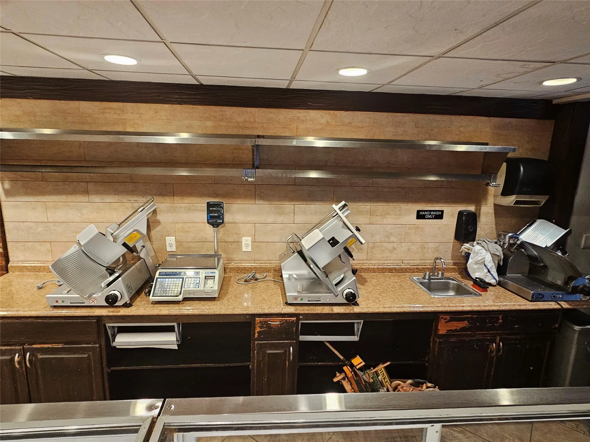 Kitchen featuring a paneled ceiling, light stone counters, a sink, and dark brown cabinetry Kitchen featuring a paneled ceiling, light stone counters, a sink, and dark brown cabinetry
