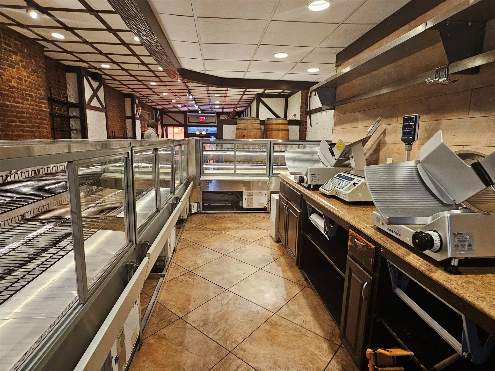 Kitchen featuring a paneled ceiling, brick wall, recessed lighting, light tile patterned floors, and light countertops Kitchen featuring a paneled ceiling, brick wall, recessed lighting, light tile patterned floors, and light countertops