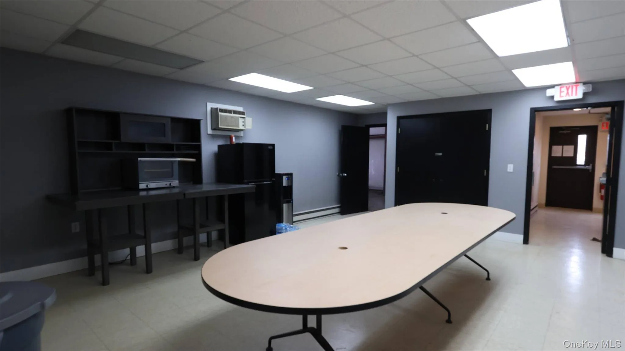 Game room featuring a wall unit AC, a baseboard heating unit, a drop ceiling, and light floors Game room featuring a wall unit AC, a baseboard heating unit, a drop ceiling, and light floors