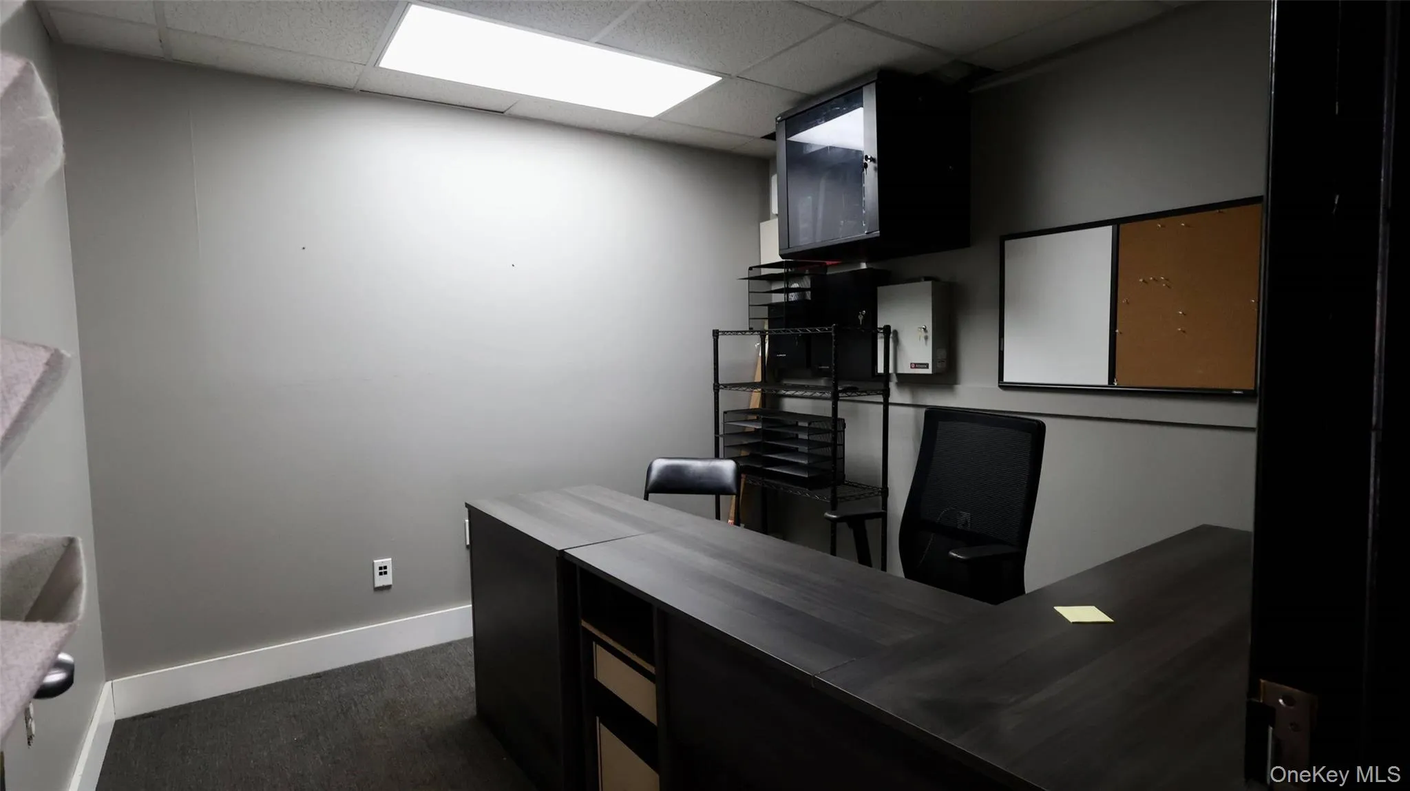 Office space with dark carpet, a drop ceiling, and baseboards Office space with dark carpet, a drop ceiling, and baseboards