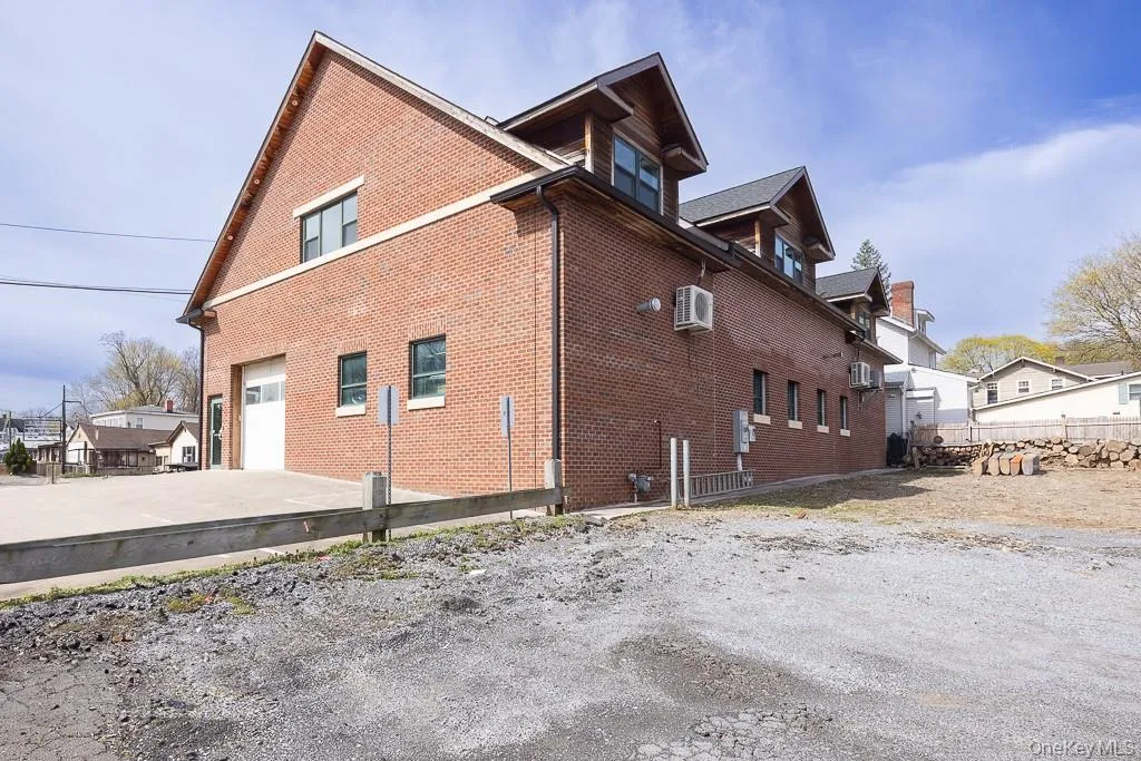 View of property exterior featuring a garage, fence, brick siding, driveway, and a wall unit AC View of property exterior featuring a garage, fence, brick siding, driveway, and a wall unit AC