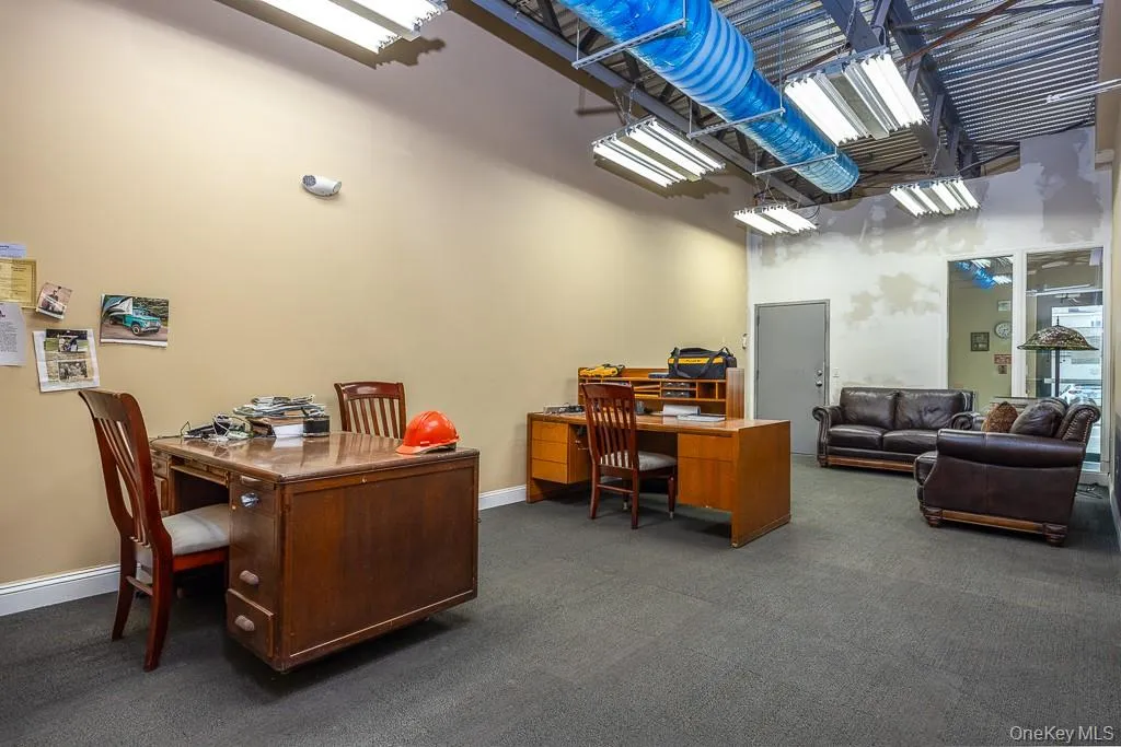 Office area featuring dark carpet, a towering ceiling, and baseboards Office area featuring dark carpet, a towering ceiling, and baseboards