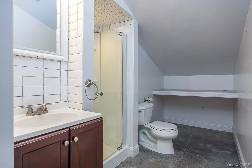 Full bathroom with toilet, vanity, baseboards, and a shower stall Full bathroom with toilet, vanity, baseboards, and a shower stall