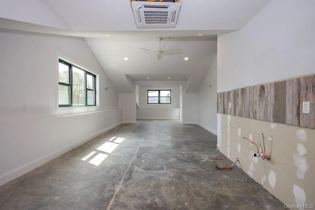 Additional living space featuring baseboards, recessed lighting, vaulted ceiling, and unfinished concrete floors Additional living space featuring baseboards, recessed lighting, vaulted ceiling, and unfinished concrete floors