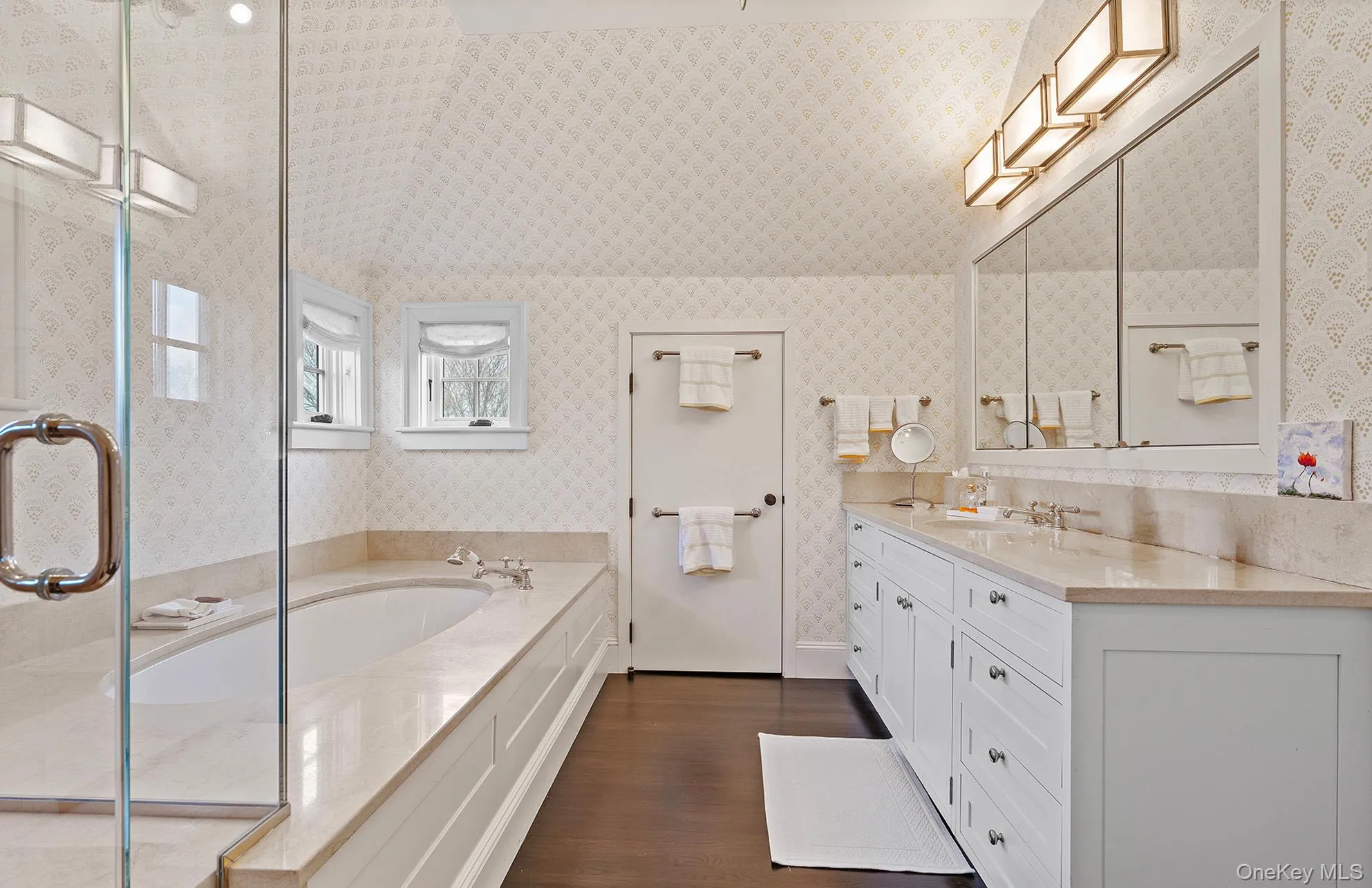 Bathroom with a garden tub, a shower stall, vanity, wood finished floors, and wallpapered walls Bathroom with a garden tub, a shower stall, vanity, wood finished floors, and wallpapered walls