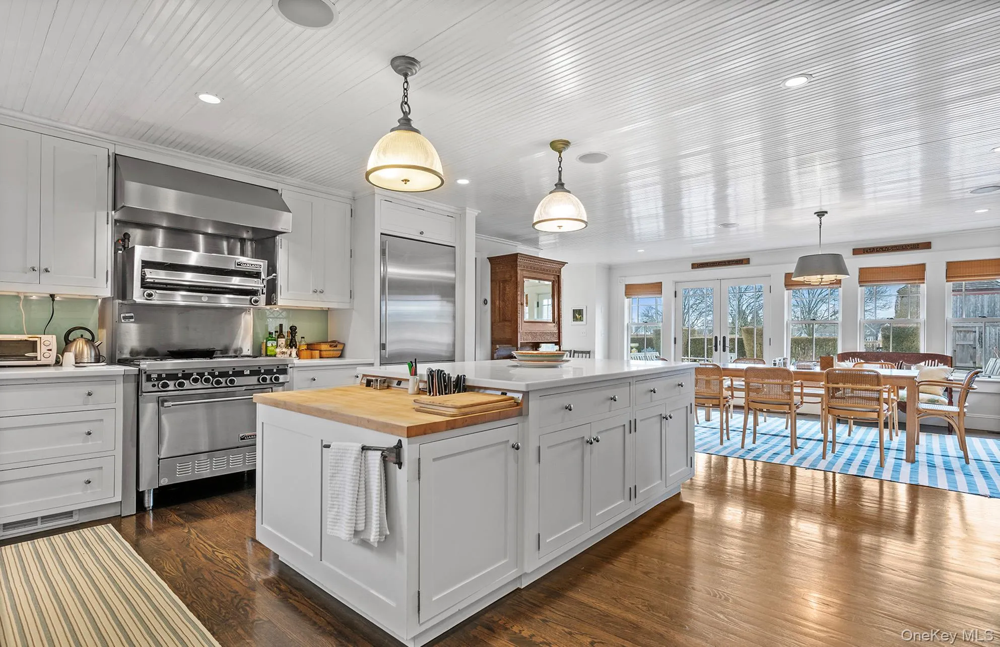 Kitchen with high end appliances, wall chimney range hood, a kitchen island, wood counters, and dark wood-style floors Kitchen with high end appliances, wall chimney range hood, a kitchen island, wood counters, and dark wood-style floors