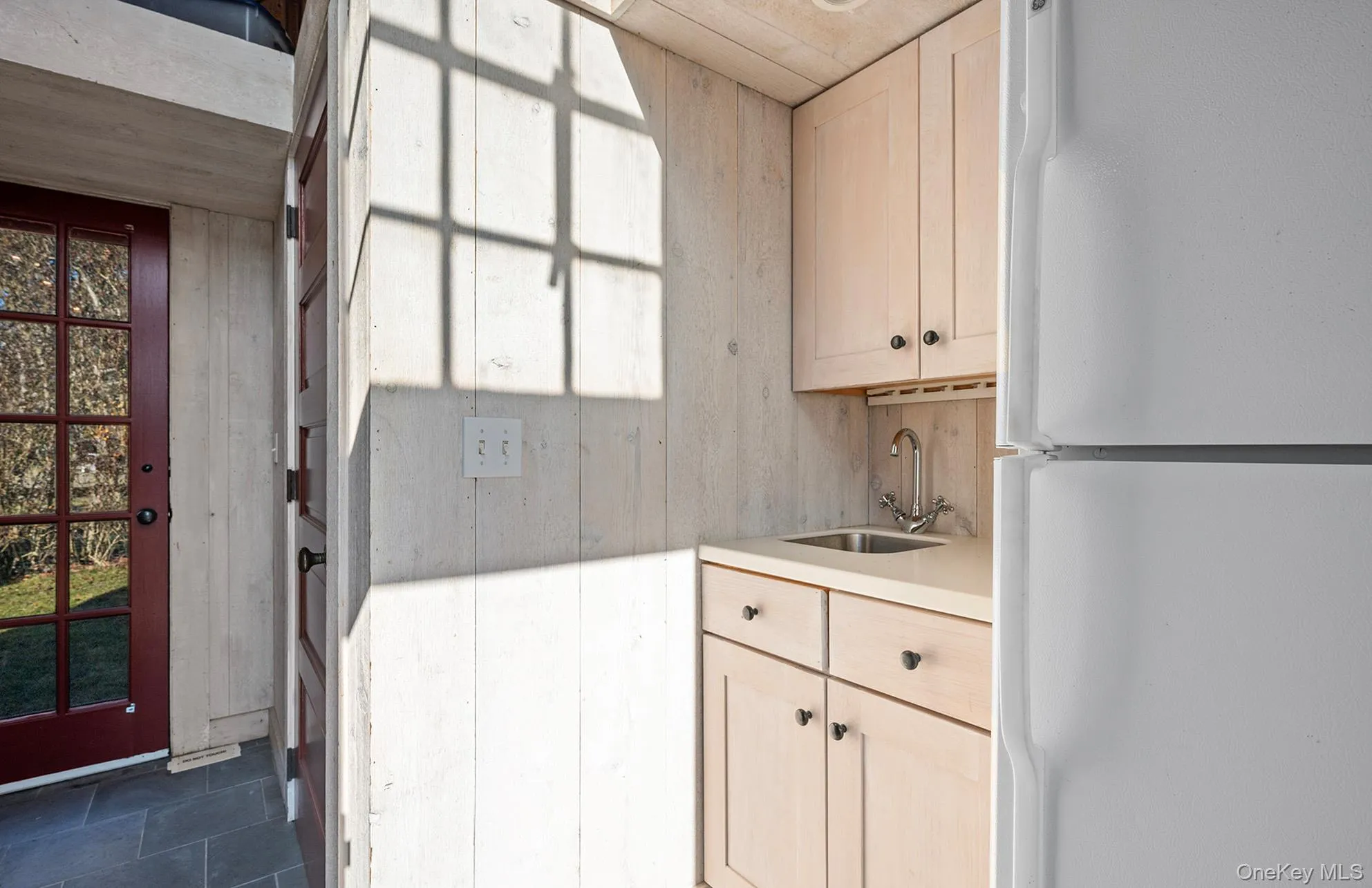 Kitchen with freestanding refrigerator, a wealth of natural light, dark tile patterned flooring, light countertops, and a sink Kitchen with freestanding refrigerator, a wealth of natural light, dark tile patterned flooring, light countertops, and a sink