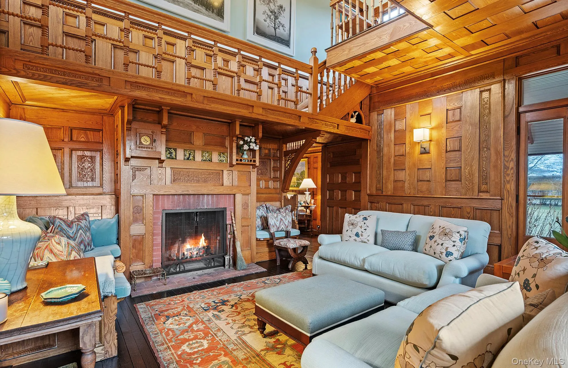 Living room featuring hardwood / wood-style floors, a high ceiling, a brick fireplace, wooden walls, and built in shelves Living room featuring hardwood / wood-style floors, a high ceiling, a brick fireplace, wooden walls, and built in shelves