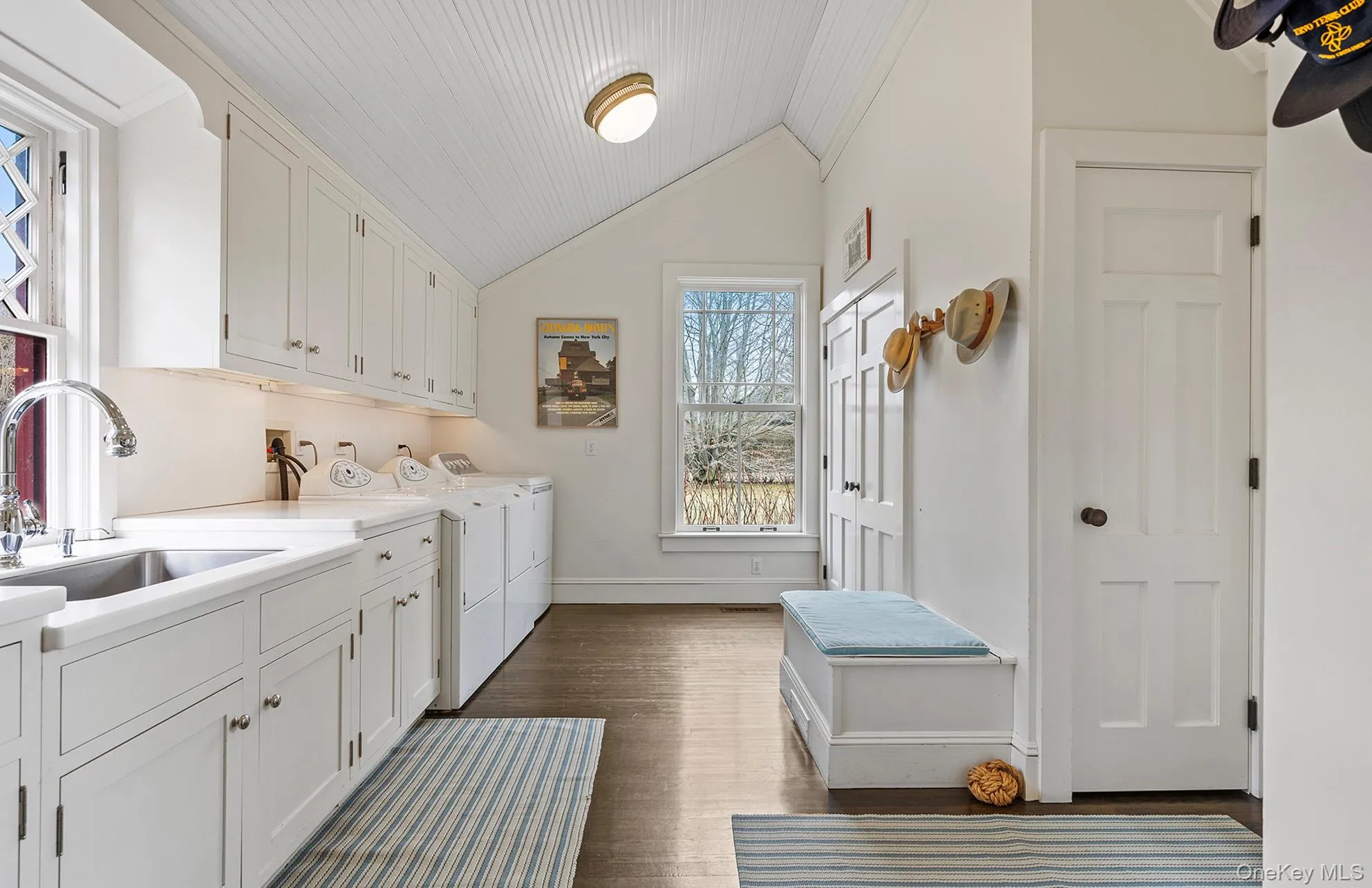 Washroom featuring baseboards, dark wood-style floors, washer and clothes dryer, cabinet space, and a sink Washroom featuring baseboards, dark wood-style floors, washer and clothes dryer, cabinet space, and a sink