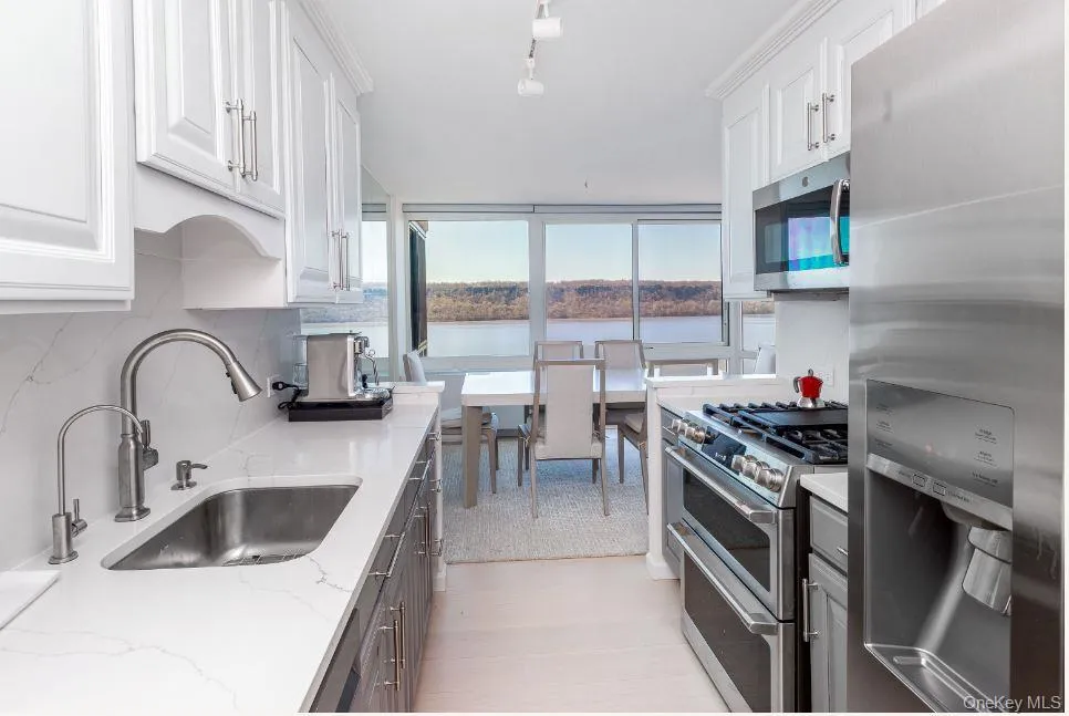 Kitchen with stainless steel appliances, white cabinets, a sink, and decorative backsplash Kitchen with stainless steel appliances, white cabinets, a sink, and decorative backsplash