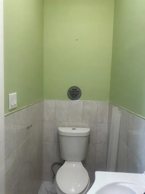 Half bath featuring tile walls, a wainscoted wall, and toilet Half bath featuring tile walls, a wainscoted wall, and toilet