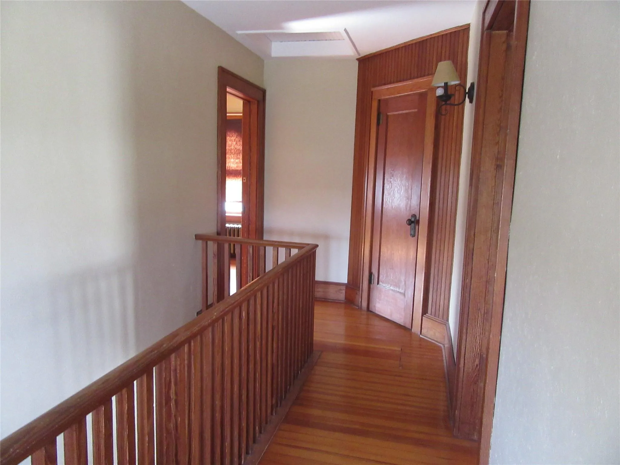 Corridor featuring an upstairs landing and wood finished floors Corridor featuring an upstairs landing and wood finished floors