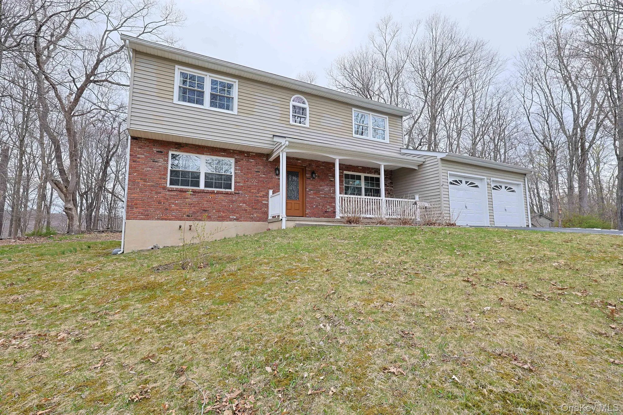 The property features brick and siding exterior, a front porch with white railings, and a two-car garage The property features brick and siding exterior, a front porch with white railings, and a two-car garage