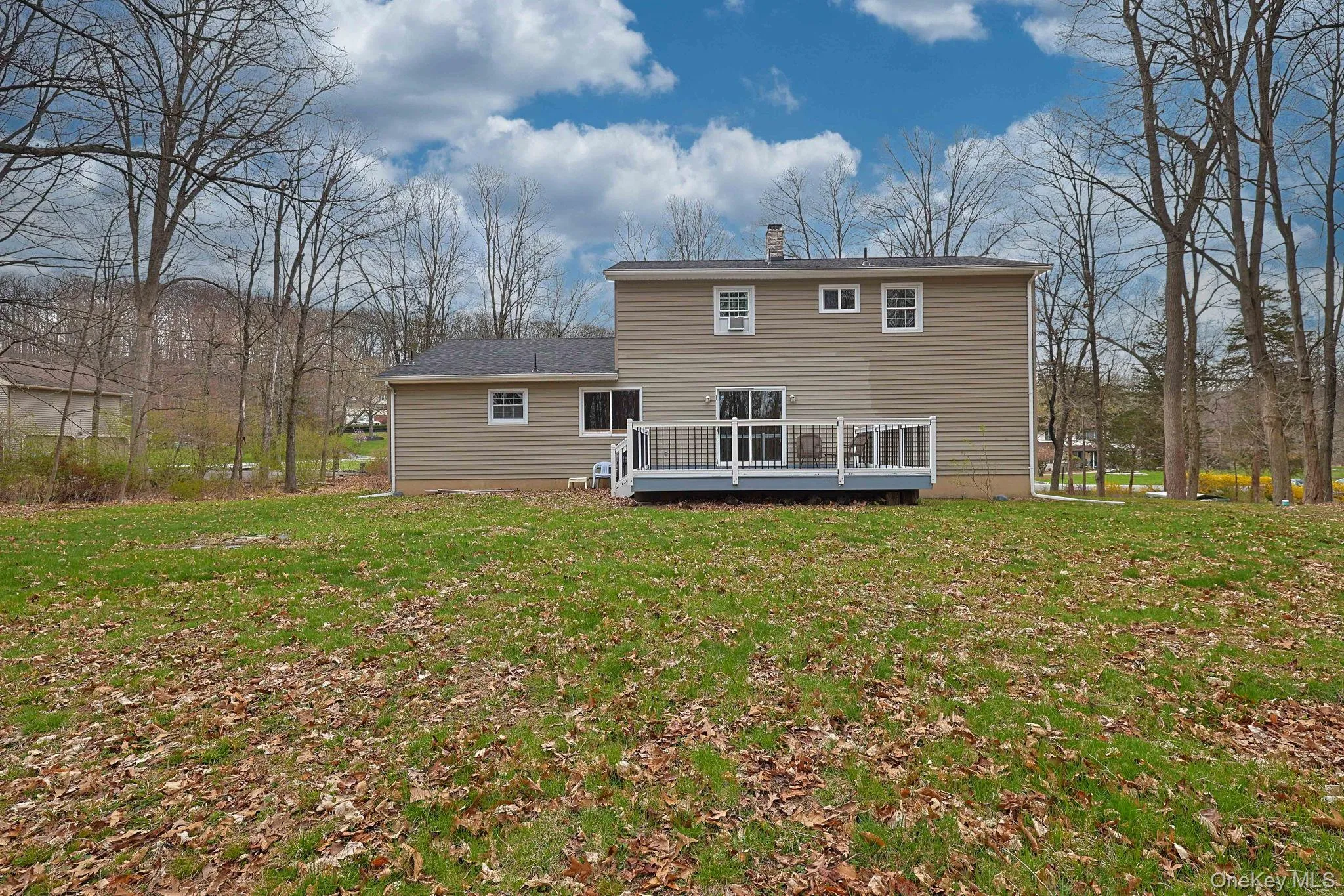 The property features a spacious yard with a green lawn and a deck with railings The property features a spacious yard with a green lawn and a deck with railings